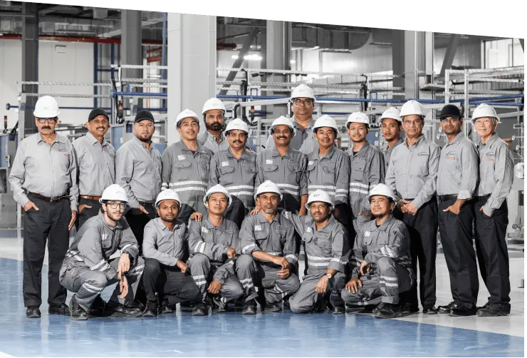 Arab Basalt Fiber Company team posing inside the factory, wearing work suits and helmets